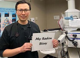 Dr. Tyan holding up a My Radon Story sign in his lab