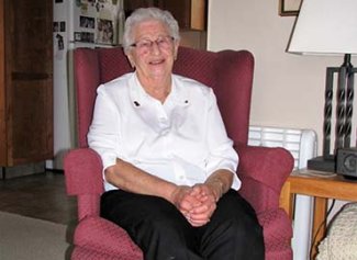 Mary sitting on a red chair smiling